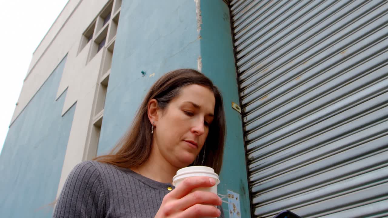 도시 4k에서 휴대 전화를 사용하는 행복한 여성의 낮은 각도 뷰