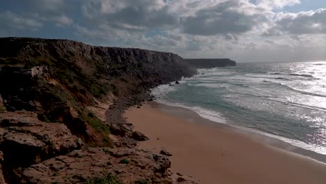 Magnífico-Paisaje-De-Una-Playa,-Con-Las-Olas-Rompiendo-En-La-Arena-Blanca,-Rodeada-De-Acantilados