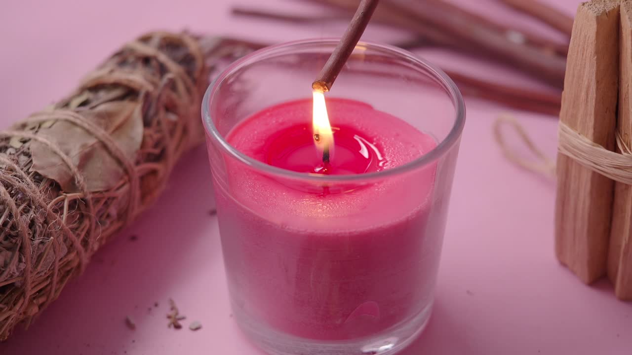 Accensione di bastoncino di Palo Santo con fiamma di candela rosa