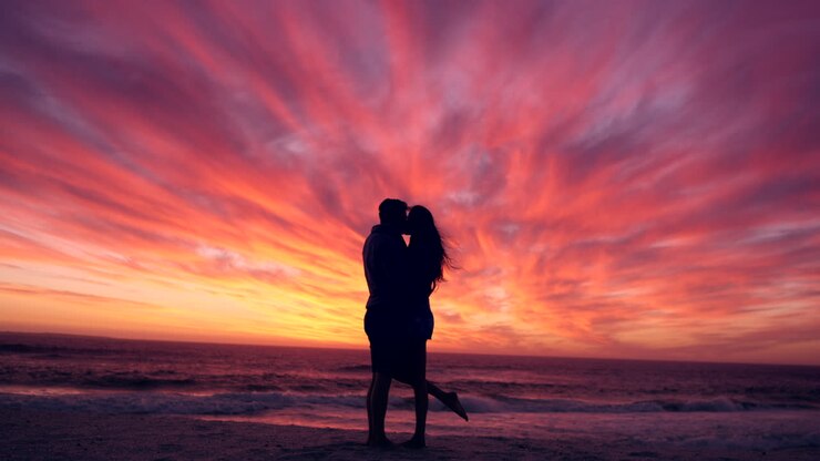 Coppia, silhouette con bacio sulla spiaggia al tramonto