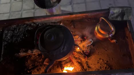 traditional tea making on fire boiling water kettle and brew black tea herbal tea on bonfire smoke taste tasty hot drink in cold desert climate in autumn winter season in iran countryside rural life