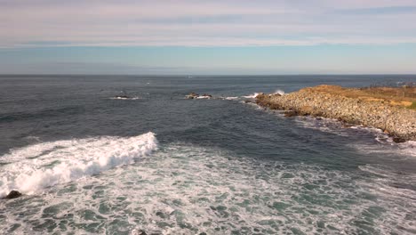 revelación de olas blancas espumosas que llegan a tierra suavemente en una playa rocosa con vistas al mar en un día brillante