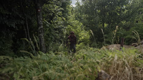 un joven excursionista caminando por un sendero estrecho en el bosque hasta el mirador