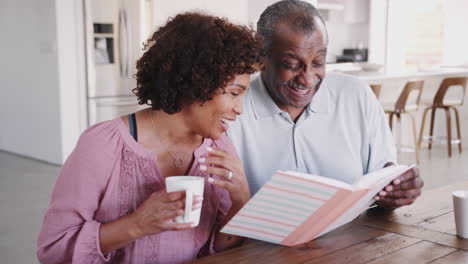 Middle-aged-black-woman-and-her-dad-looking-through-photo-album-together-at-home,-close-up