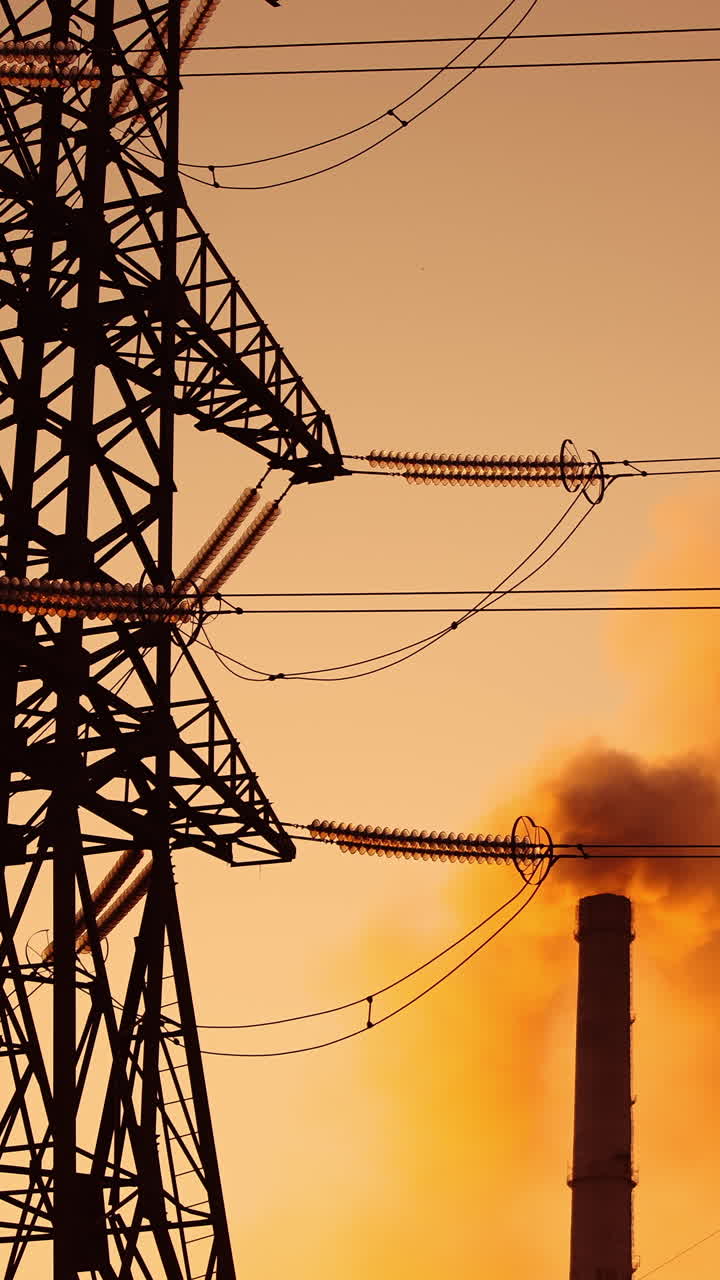 Polluting factory at dawn. Electric towers next to dirty smoke emitting from factory pipes at sunset. Climate change. Ecological disaster. Vertical video
