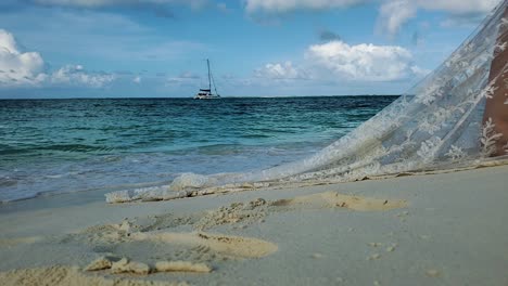 footprints on white sand beach and newywed barefoot couple holding hands, close up