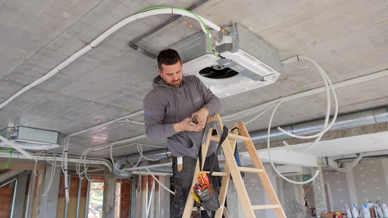 Tecnico HVAC installa unità di condizionamento sul soffitto