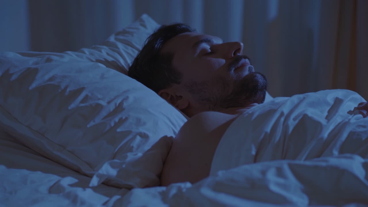 A serene video scene of a man sleeping peacefully in low light