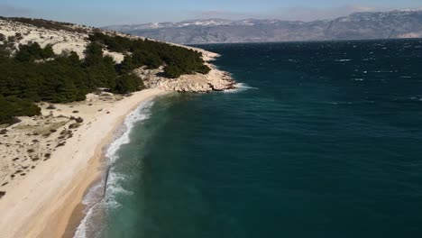 Aerial-shot-with-dolly-to-the-right-over-the-adriatic-sea-on-the-beach-of-Baska-Croatia-4k-full-colors