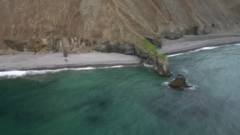 calm ocean swashing into the beach, eroded dyke stands as a barrier