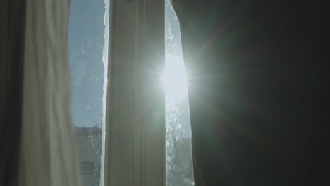 Beautiful-slow-motion-shot-of-a-young-man-opening-his-bedroom-curtains-to-let-sunlight-in-during-sunrise