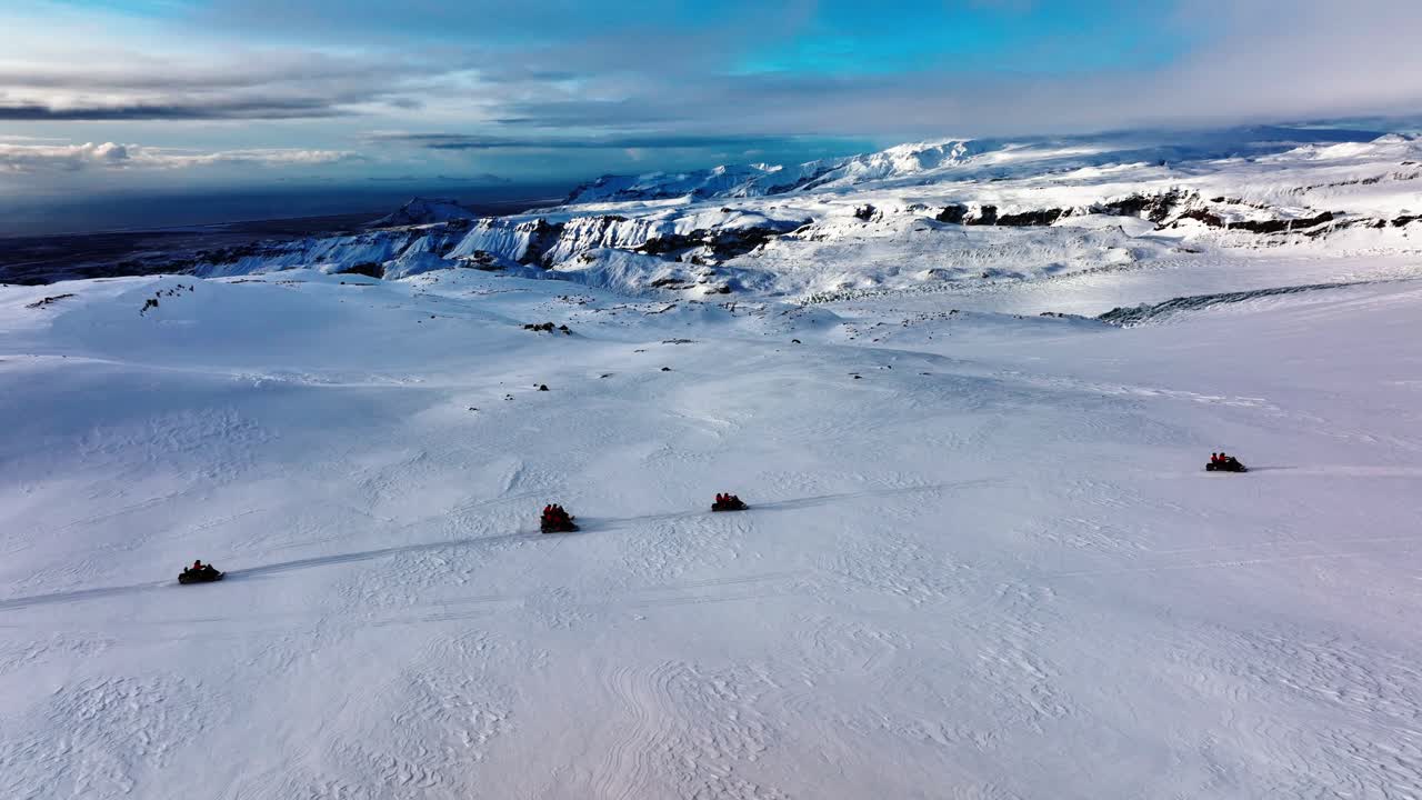 vista panorámica aérea del paisaje de personas montando motos de nieve en el glaciar myrdalsjokull en islandia, al atardecer