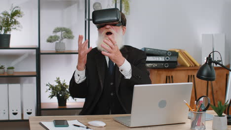 Senior-business-man-in-VR-goggles-watch-virtual-reality-video,-working-on-simulation-game-at-office