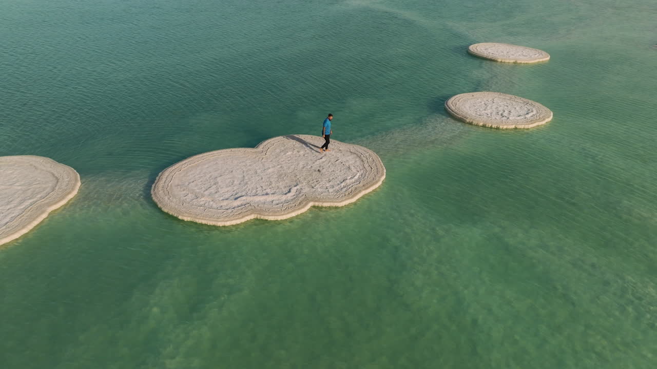 hombre caminando sobre una placa de sal sólida en el mar muerto en israel