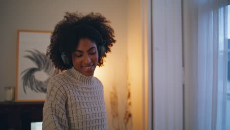 Earphones-woman-enjoying-music-at-evening-flat.-African-carefree-lady-dancing