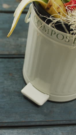 video of white compost bin with organic waste and copy space on grey wooden background