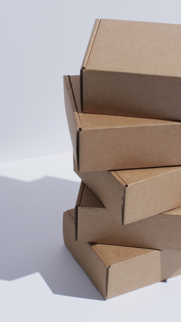 Vertical video of stacked cardboard boxes with copy space over white background