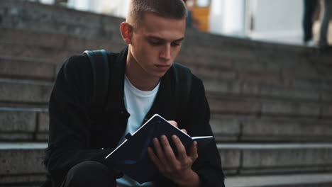 young student writing notes outdoors.