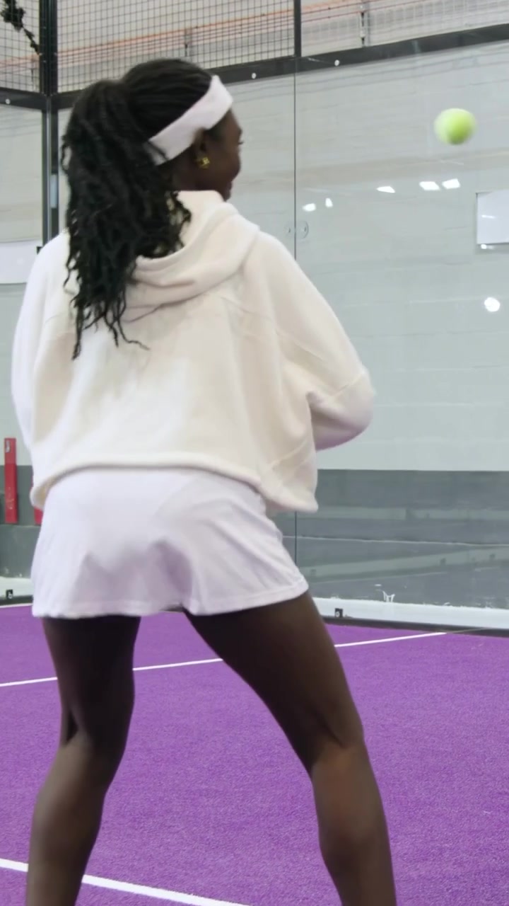 Vertical video: Offering ball coach guiding student white hoodie hitting racket for form on court