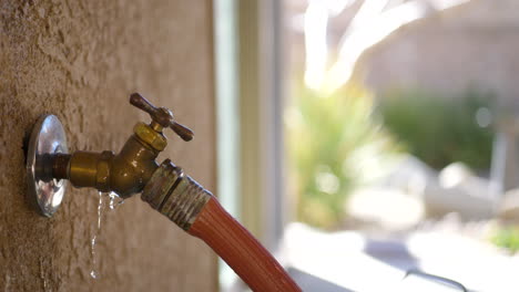 Turning-off-a-leaking-hose-faucet-to-conserve-water-and-not-waste-it-in-a-California-drought-while-spraying-and-leaking