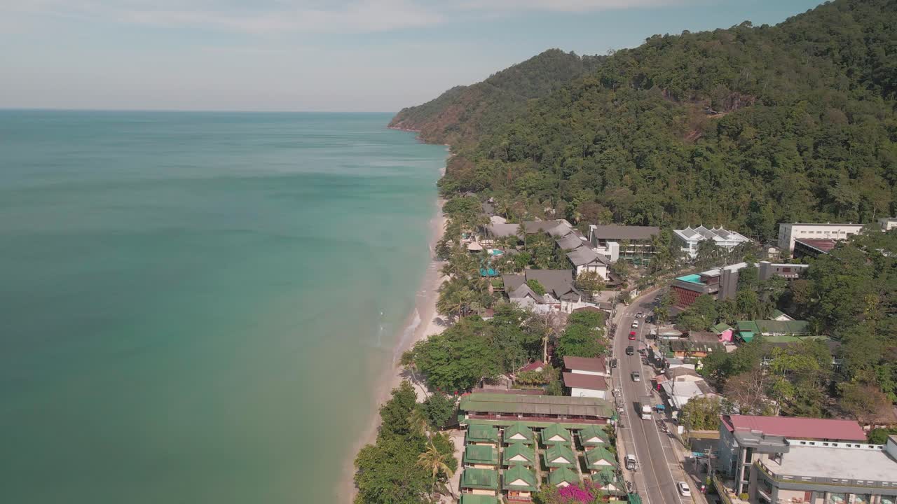 vista aérea de la carretera y los hoteles-resorts de playa que se extienden en la playa costera de un océano