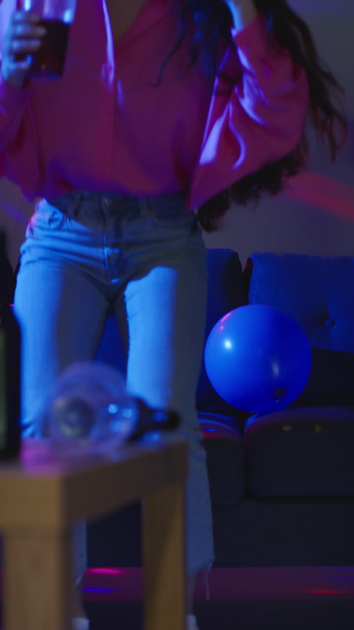 Vertical Video Of Drunk Woman Getting Up From Sofa Drinking Alcohol At House Party