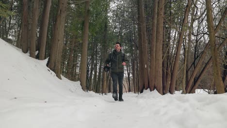 Toma-Estática-Baja-De-Un-Excursionista-En-Un-Denso-Bosque-Invernal-Cubierto-De-Nieve-Caminando-Hacia-La-Cámara