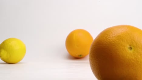 frutas cítricas de naranja, limón y lima brillantes y frescas que caen y rebotan sobre fondo blanco en cámara lenta
