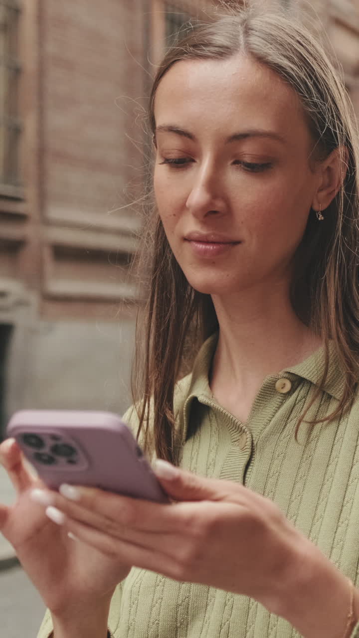 Giovane donna sorridente mentre usa lo smartphone all'aperto