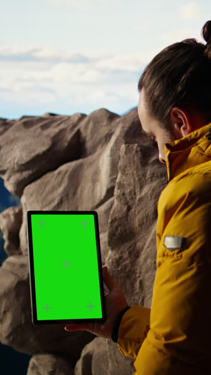 Man Holding Green Screen Tablet in Mountain Landscape