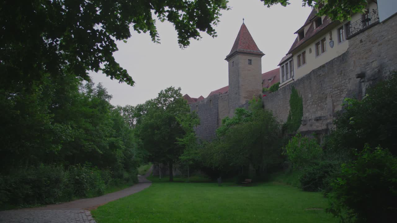 Green park with pathway along medieval city walls and tower in Rothenburg ob der Tauber, Germany