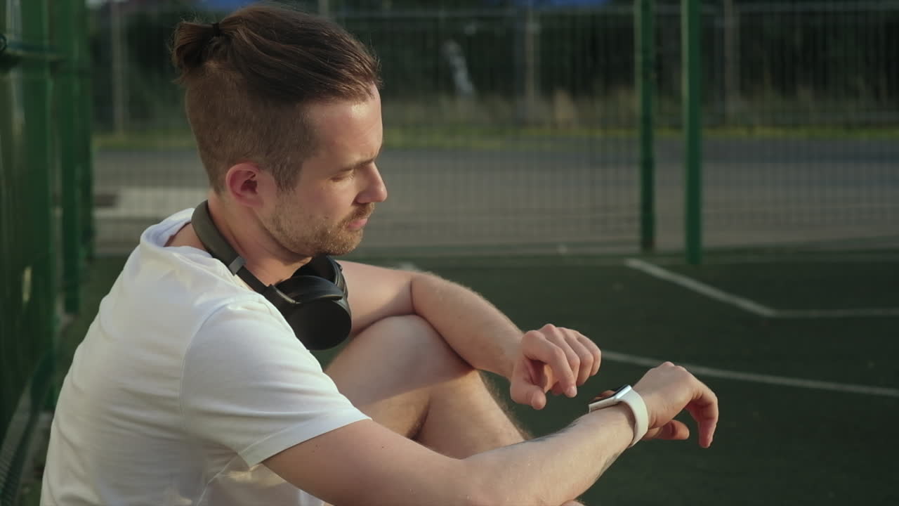 스포츠 경기장에서 스마트워치를 확인하는 남자