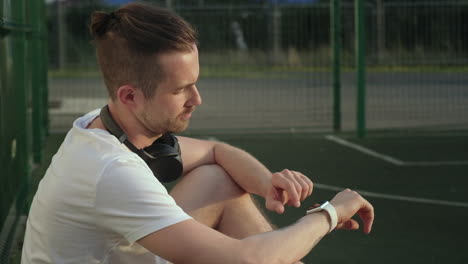 man checking smartwatch on sports field