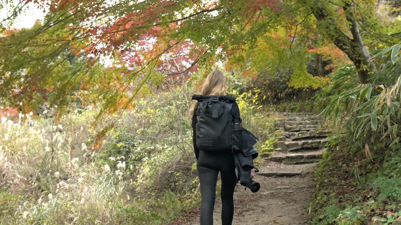 A woman peacefully hiking along the historic Nakasendo Trail in Japan, surrounded by picturesque mountain landscapes and traditional Japanese villages.
