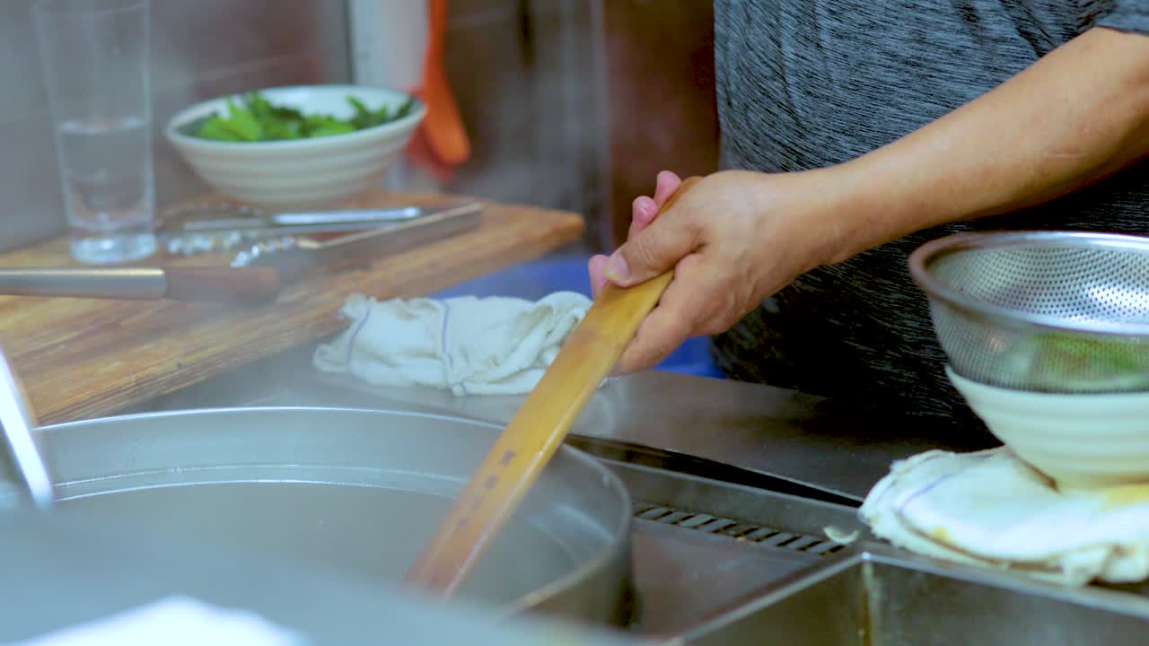 Chef prepares noodle soup with meatballs