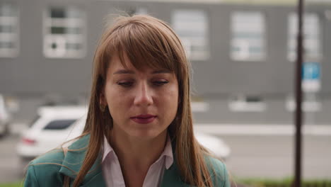 mujer pensativa con cabello largo camina hacia el edificio contra el coche