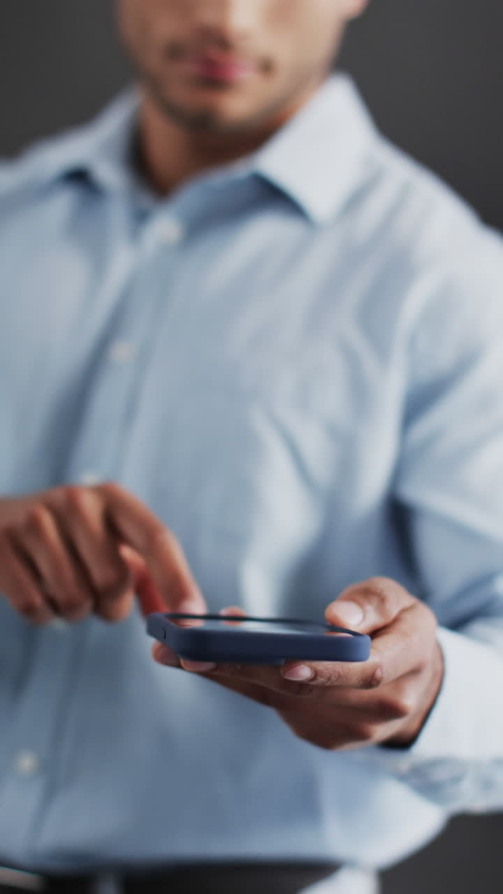 Vertical video of biracial businessman using smartphone and holographic display, copy space