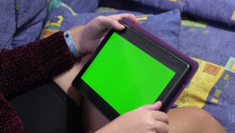 cámara portátil: punto de vista de la mujer en una habitación moderna sentada en una silla usando un teléfono con pantalla de maqueta verde tecla de croma surfando por internet viendo vídeos de contenido blogs tocando en la pantalla central