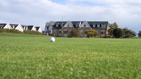 ground level shot of a golf ball on the green. golfer shadow seen as they walk past.