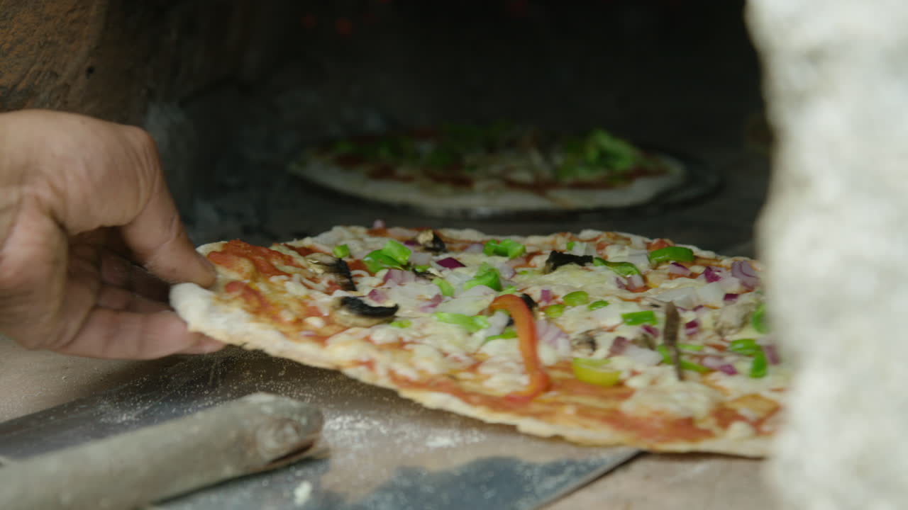 mano pone pizza en paleta y empuja en horno de ladrillo, primer plano, 60fps