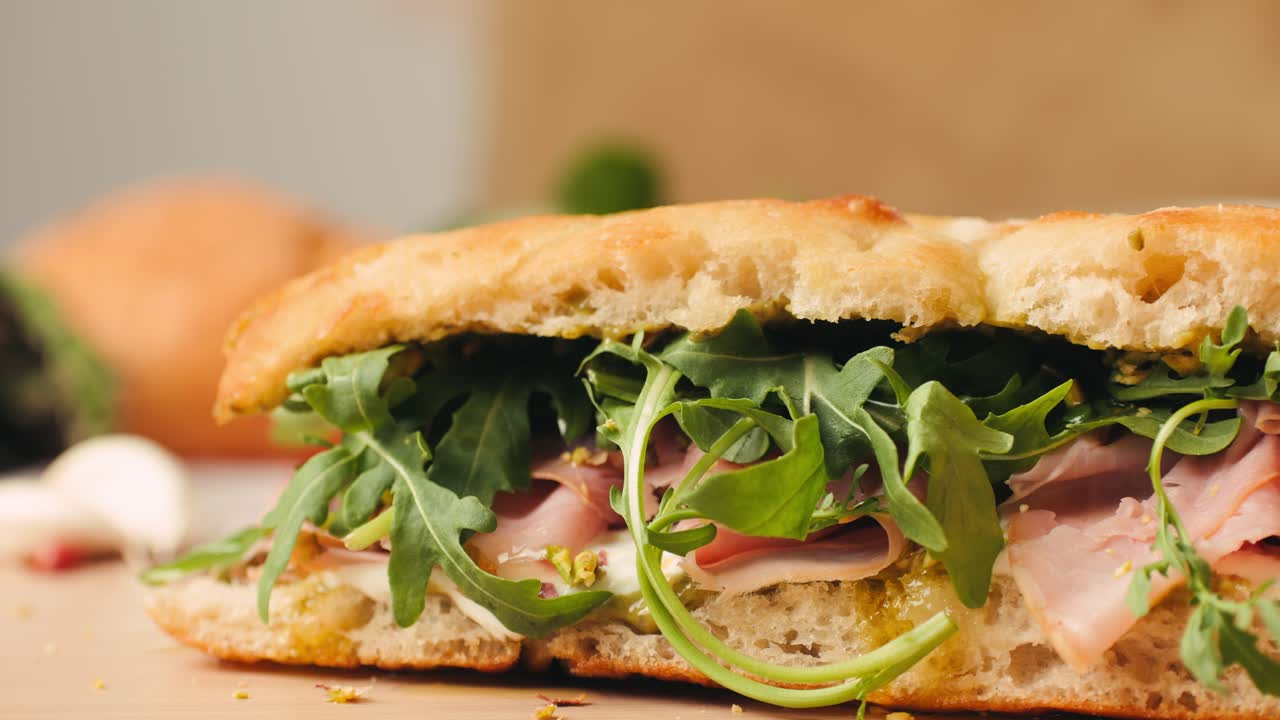 Mortadella ham sandwich, Traditional italian focaccia filled with thin pesto slices of mortadella, served by chef man in cafe restaurant. Macro of traditional italian spanish tapas antipasti.