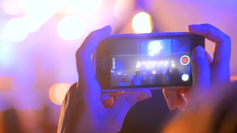 silueta de las manos grabando video de un concierto de música en vivo con un teléfono inteligente