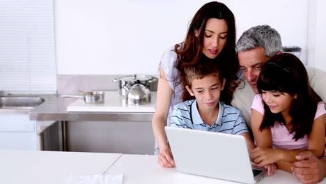 Familia-Mirando-La-Computadora-Portátil-En-La-Cocina