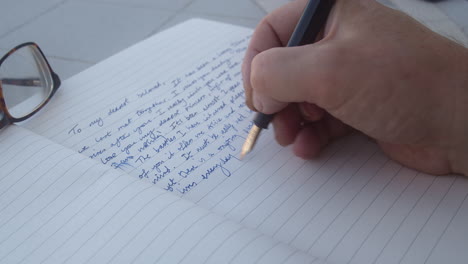 male hand writing down memoir on a journal with a fountain pen