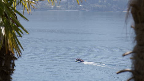 speedboat sailing across the lake como on a sunny day in tremezzo, lombardy, italy, wide shot