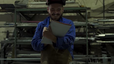 mecánico feliz en el taller escribiendo notas en el bloc de notas