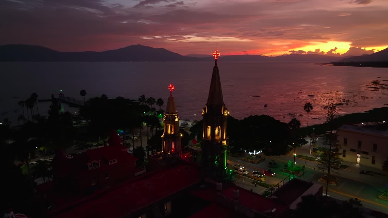 Orbit aerial at nighttime of Saint Francis Parish, Town Hall, Lake Chapala and city center. 360 view. City decorated for Mexico Independence Day