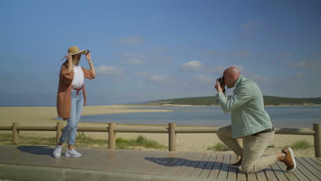 Man-photographing-beautiful-girlfriend-on-beach