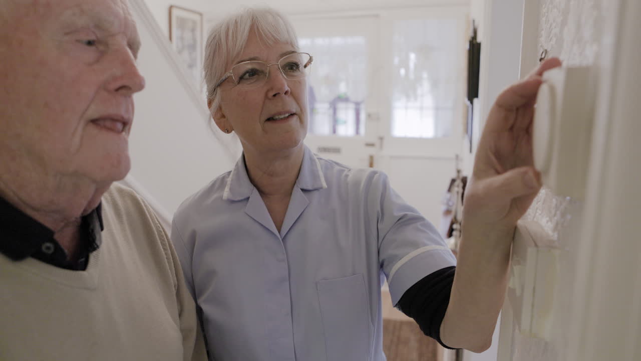 Nurse adjusts thermostat for older man in home