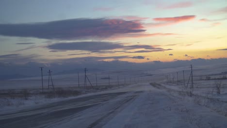 a snowy country road at sunset